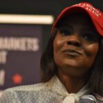 woman in a red cap speaking into a microphone