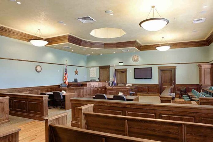 shutterstock_1349439551-2 Empty courtroom with wooden benches and judge's bench