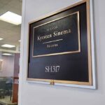 Senators Bodyguard RANSACKS Her Home Office door plaque with gold trim outside a glass-walled conference room