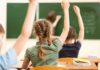 students raising hands in a classroom