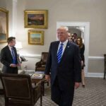 Trump Conducted 327 Trades Day Before Tariff Push! Donald Trump walks through an office with Sean Lawler nearby and Mariano Rajoy following behind