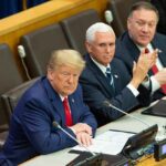 three men in suits seated at a conference table