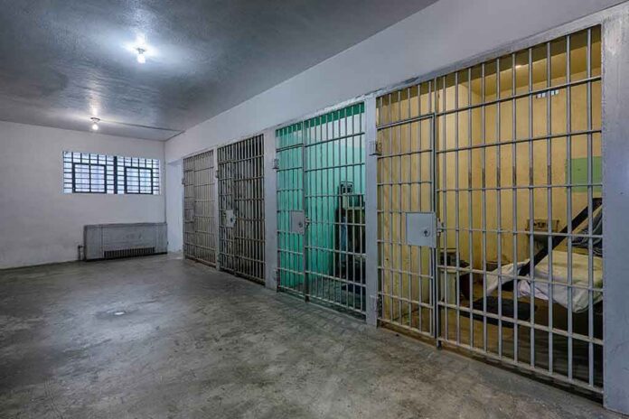 Interior view of a prison cell block with metal bars and concrete flooring