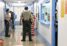 Corrections officers escort an inmate in a jail hallway