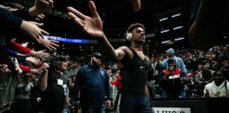 Basketball player in arena high-fives fans while wearing headphones