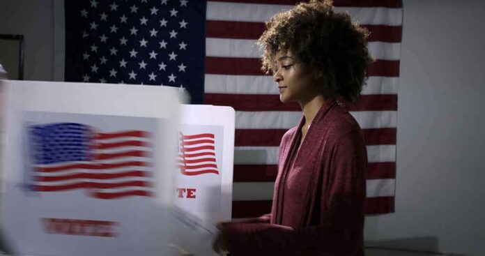 Voter at a polling booth with an American flag backdrop