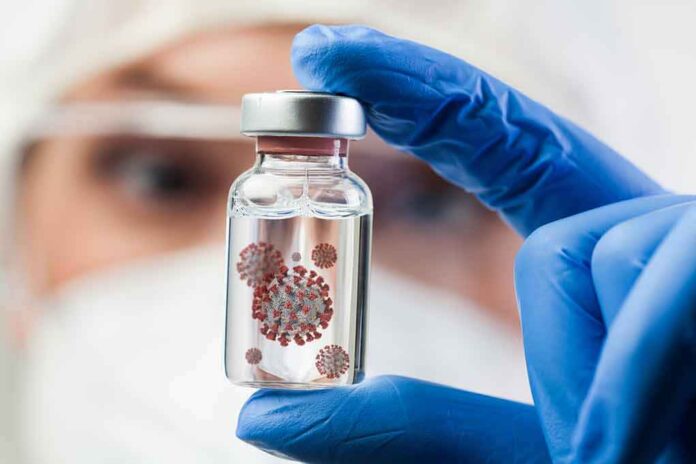 Gloved hand holding a small vial in a lab