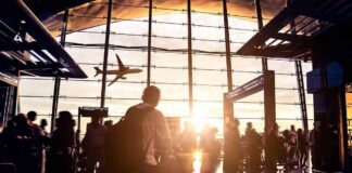 Airport terminal crowd at sunset with airplane silhouette outside
