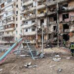 Damaged apartment building behind a playground slide