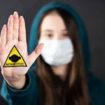 Person in mask holding up palm with monkeypox warning patch