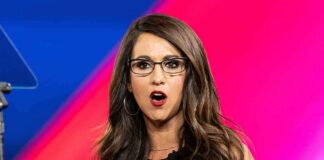 Woman with glasses speaking on stage with colorful backdrop