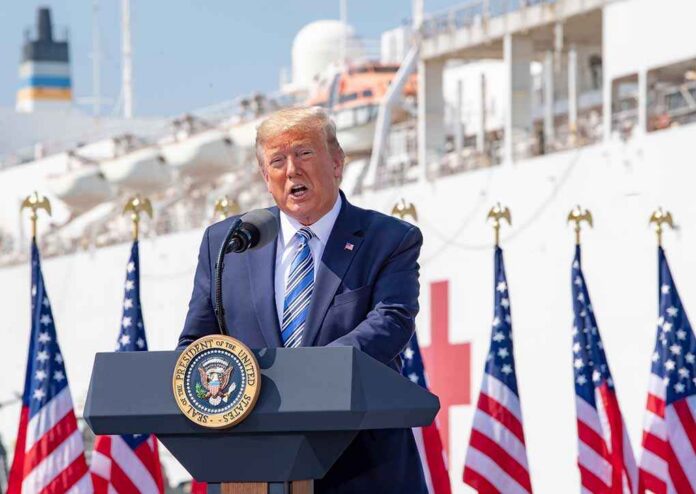 President,Donald,J.,Trump,Delivers,Remarks,During,His,Visit,To Donald Trump speaking at a podium with American flags and a ship in the background
