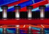 Debate stage with four empty podiums and bright red and blue backdrop