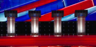 Debate stage with four empty podiums and bright red and blue backdrop