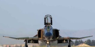 Military jet taxiing on runway with open canopy
