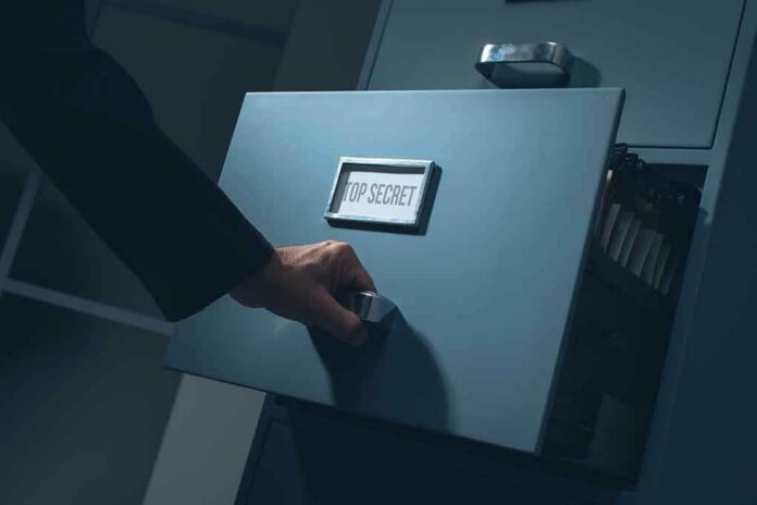 shutterstock_704562664 Hand opening a filing cabinet drawer labeled top secret