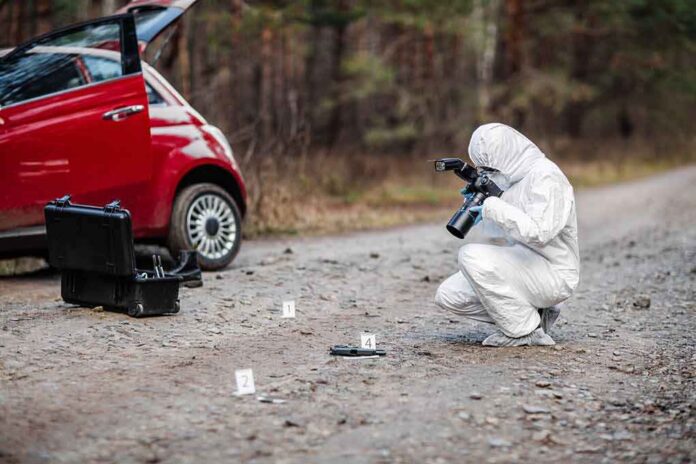 Forensic investigator photographing evidence near a red car on a rural road