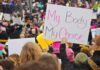 Whispered Abortion Regret Sparks Criminal Summons Protesters hold signs at a crowded march