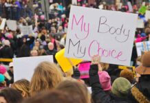 Whispered Abortion Regret Sparks Criminal Summons Protesters hold signs at a crowded march