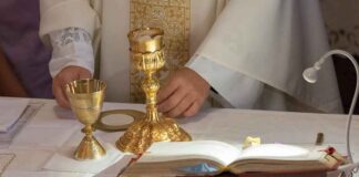 Priest at altar with chalices and open book