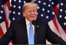 Nude Gold Trump Statue Appears in Gvb Building Donald Trump speaking at a podium with U.S. flags in the background