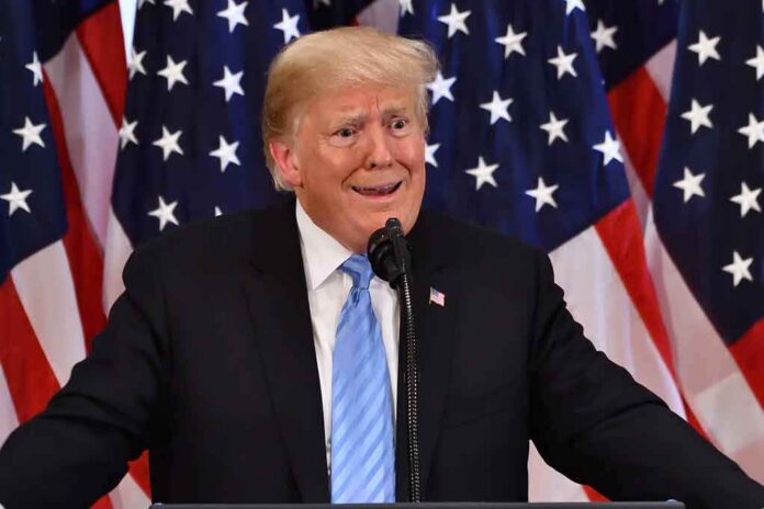 shutterstock_1190031697 Donald Trump speaking at a podium with U.S. flags in the background