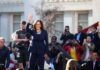 Kamala Harris waves on stage at an outdoor event; Povilas Vanagas is present among the crowd