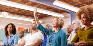 Brian Yorkey in a community meeting as a woman raises her hand