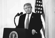 Trump Asked If He’d Accept Midterm Results Donald Trump at a podium with microphone and U.S. flag in background