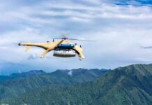 Cargo drone helicopter flying over green mountain range