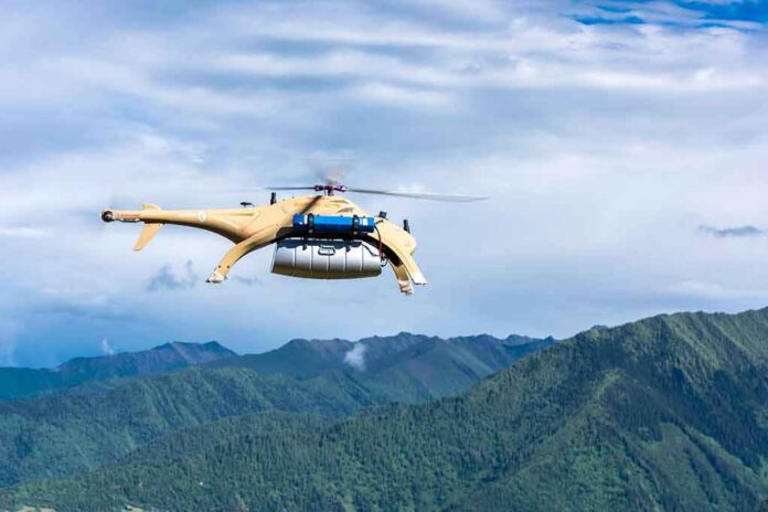 Cargo drone helicopter flying over green mountain range