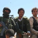 Three armed men standing outdoors