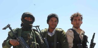 Three armed men standing outdoors