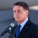 man in suit speaking at a microphone