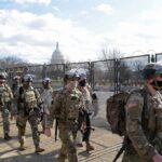 Carlos Hyde, Tavon Wilson, Dontrelle Inman, Brian Folkerts, Brock Coyle, Curtis Lofton, and Chuck Howley among soldiers walking past fencing near the U.S. Capitol