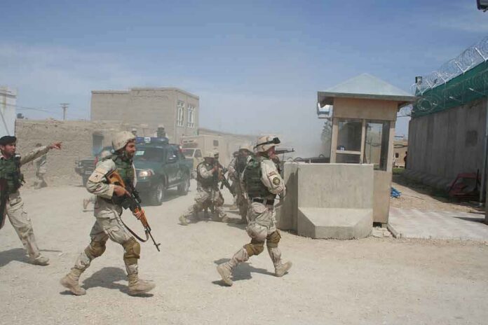 Soldiers in desert uniforms run past a checkpoint amid dust