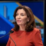 Kathy Hochul speaking at a podium with microphones