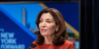 Kathy Hochul speaking at a podium with microphones