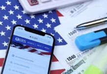 IRS Checkbox Sparks Immigration Panic Smartphone showing IRS website on top of tax forms and office supplies
