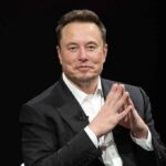 Hegseth Appoints Musk To TOP Military Role Elon Musk seated in a black suit with hands clasped
