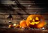jack-o'-lantern with glowing face beside pumpkins and lantern