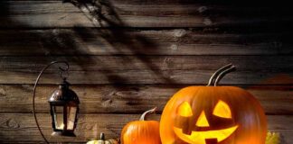 jack-o'-lantern with glowing face beside pumpkins and lantern