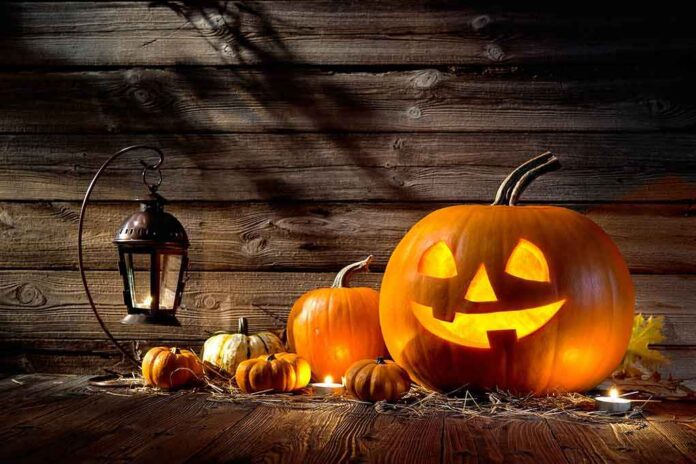 shutterstock_283016600 jack-o'-lantern with glowing face beside pumpkins and lantern