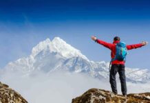 Hikers TRAPPED On Frozen Mountain – 36 Hours Hiker with arms raised facing snowy mountain peak