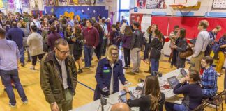 Don MacLean in a busy gymnasium voting station with check-in tables