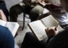 Hands holding open books in a small discussion circle