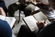 Hands holding open books in a small discussion circle