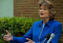 Lisa Murkowski speaking at an outdoor press conference with microphones in front