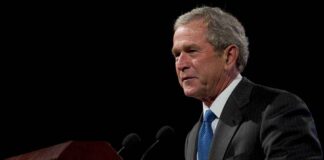 George W. Bush speaking at a podium with microphones