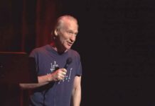Bill Maher performing stand-up with a microphone on stage